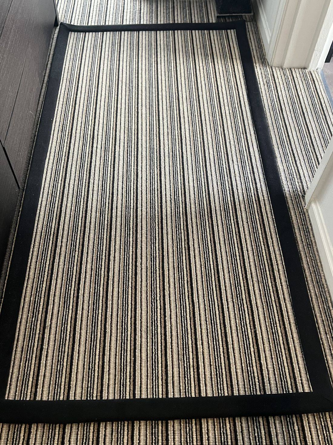 A striped hallway runner with a black tape edge, fitted in a Bath apartment